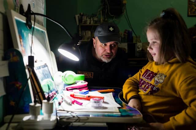 Father Vitaliy, helps a young girl with her homework in a public bomb shelter in Kharkiv. Picture: Maciek Musialek/DEC