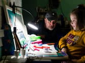 Father Vitaliy, helps a young girl with her homework in a public bomb shelter in Kharkiv. Picture: Maciek Musialek/DEC