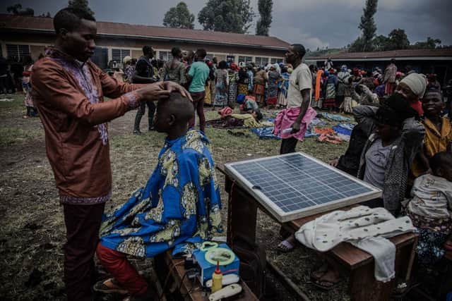A barber, an internally displaced person who fled clashes between M23 rebels and Congolese soldiers, gives a haircut to another refugee in Kanyarushinya north of Goma in DRC.