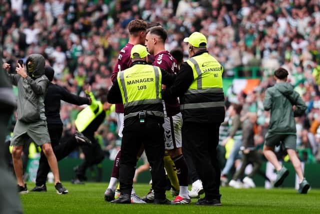 Hearts captain Lawrence Shankland is escorted from the pitch by security after Celtic fans invaded the pitch at the end of the title decider on Saturday. (Andrew Milligan/PA Wire)