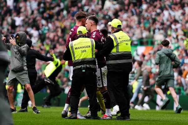 Hearts captain Lawrence Shankland is escorted from the pitch by security after Celtic fans invaded the pitch at the end of the title decider on Saturday. (Andrew Milligan/PA Wire)