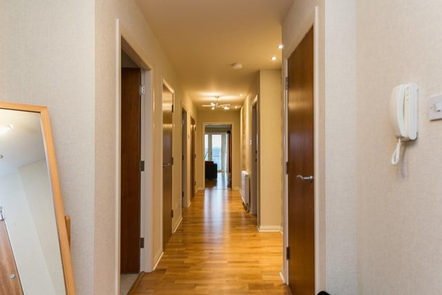 The long hall gives access throughout and features the secured entry system and three built-in store cupboards, one of which serves as a utility cupboard housing a washing machine.