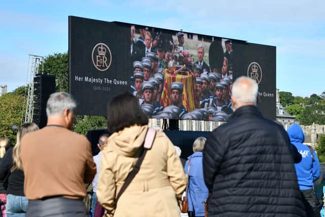 People gather to watch Queen Elizabeth II funeral on a large screen at Holyrood Park. Picture: Michael Gillen