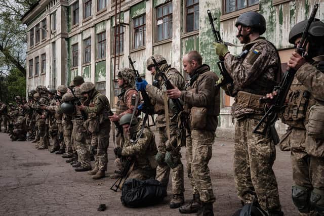 Ukrainian soldiers unload their guns as they arrive at an abandoned building to rest and receive medical treatment after fighting on the front line for two months near Kramatorsk, in eastern Ukraine