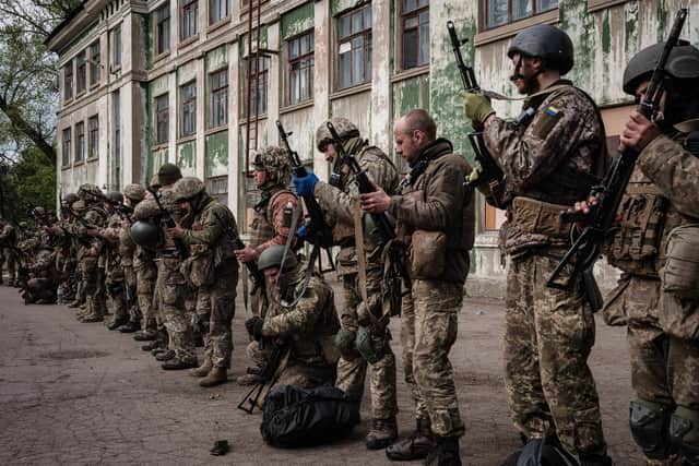 Ukrainian soldiers unload their guns as they arrive at an abandoned building to rest and receive medical treatment after fighting on the front line for two months near Kramatorsk, in eastern Ukraine