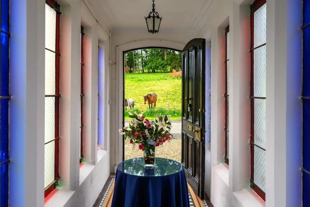 Bridged entrance hall with stained glass windows and tiled floor.