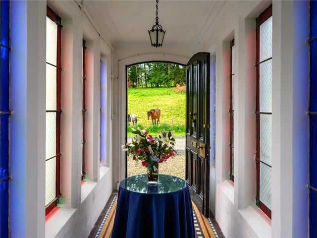Bridged entrance hall with stained glass windows and tiled floor.