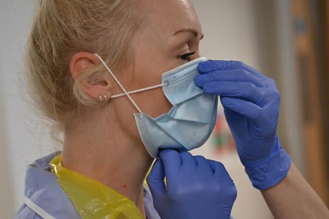 A member of clinical staff adjusts her mask. Picture: Neil Hall/AFP via Getty Images