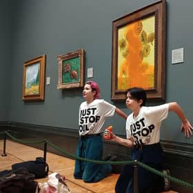 Activists with their hands glued to the wall under Vincent van Gogh's Sunflowers after throwing tomato soup on the painting at the National Gallery in central London. Picture: Just Stop Oil /AFP