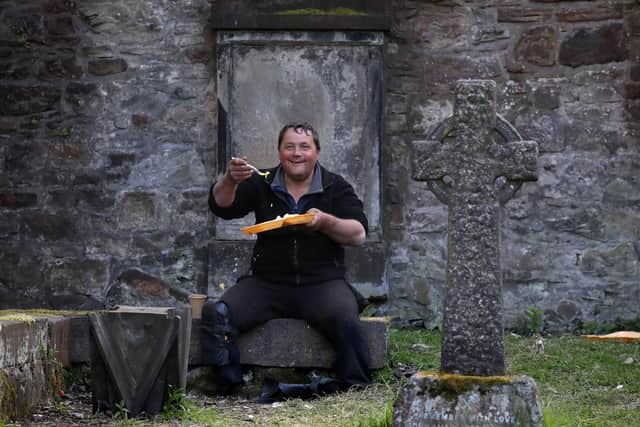 A user (name not given) of the service offered by the Step to Hope charity eats his meal in the grounds of The Parish Church of St Cuthbert in Edinburgh.