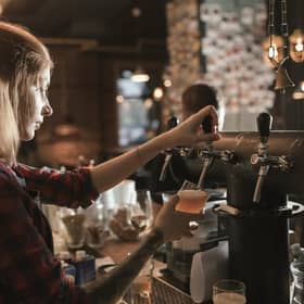 Female bartender pouring beer from tap at bar