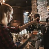 Female bartender pouring beer from tap at bar