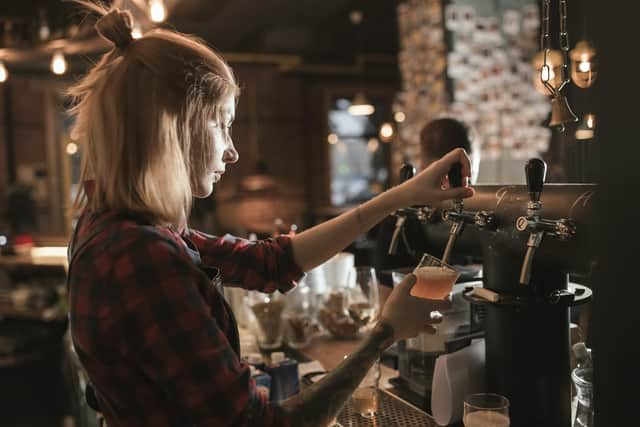 Female bartender pouring beer from tap at bar