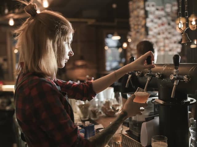 Female bartender pouring beer from tap at bar