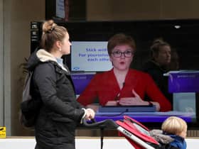 A member of the public walks past a TV screen at The Sound Counsel in Edinburgh as Nicola Sturgeon takes part in a virtual sitting of the Scottish Parliament (Picture: Andrew Milligan/PA Wire)