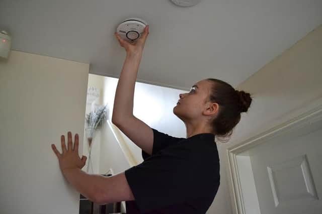 Fire and Rescue Service apprentice Jessica Lewis fitting a smoke alarm that will become compulsory next year