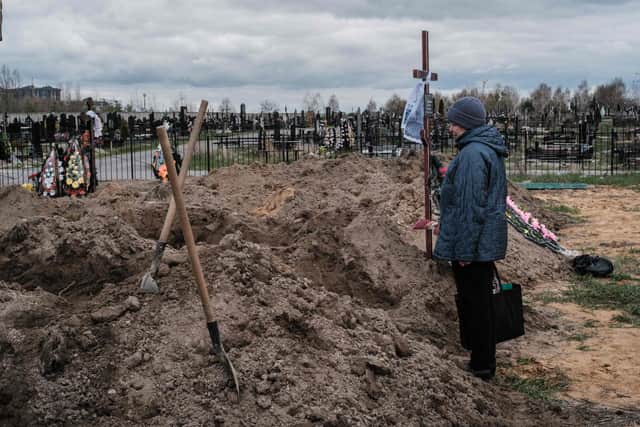 Nadia looks at the coffin of her husband who was killed, after the funeral at a cemetery in Bucha, on April 18, 2022, during the Russian invasion of Ukraine. (Photo by Yasuyoshi CHIBA / AFP via Getty Images)