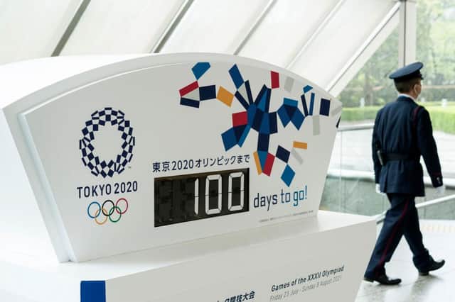 A security guard walks past a display showing 100 days to go to the Olympic games at the Tokyo Metropolitan Government.