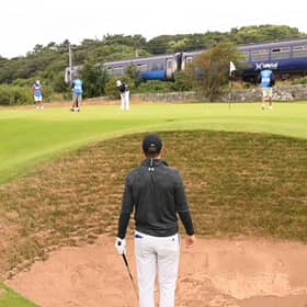 Jordan Spieth looks on from a bunker on the 11th hole as a train goes past during a practice round prior to The 152nd Open at Royal Troon. Picture: Ross Kinnaird/Getty Images.