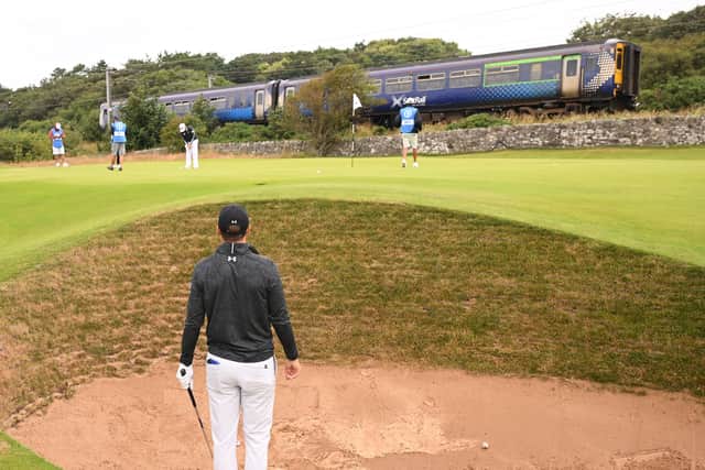 Jordan Spieth looks on from a bunker on the 11th hole as a train goes past during a practice round prior to The 152nd Open at Royal Troon. Picture: Ross Kinnaird/Getty Images.