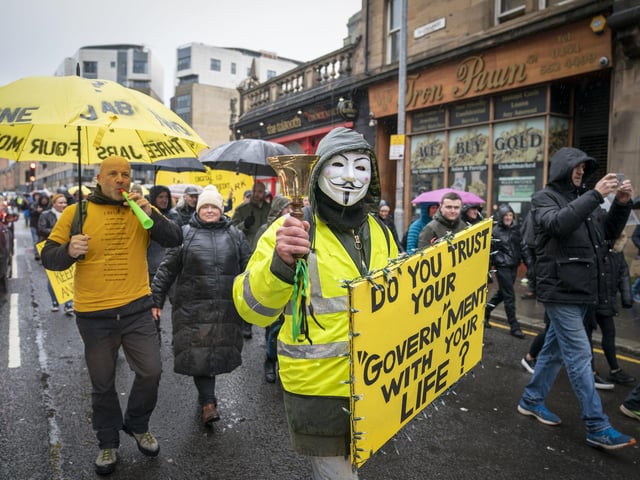 An activist holding a sign which says: "Do you trust your Govern'ment with your life?"