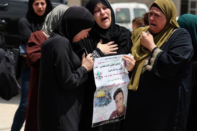 Relatives comfort Ruba al-Tamimi as she mourns her son Muhammad during his funeral procession in Deir Nizam, west of Ramallah city in the occupied West Bank, after he was shot dead during clashes with Israeli soldiers (Picture: Abbas Momani/AFP via Getty Images)