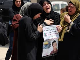 Relatives comfort Ruba al-Tamimi as she mourns her son Muhammad during his funeral procession in Deir Nizam, west of Ramallah city in the occupied West Bank, after he was shot dead during clashes with Israeli soldiers (Picture: Abbas Momani/AFP via Getty Images)