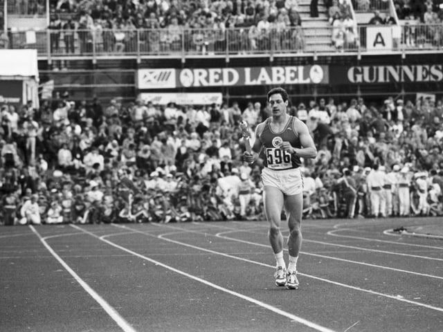 Scottish athlete Allan Wells runs in to present the Queen's Baton to Prince Philip at the opening ceremony of the Edinburgh Commonwealth Games.