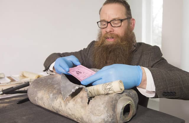 Consultant Conservator Nic Boyes opens the 1898 time capsule discovered during the move of the Burns statue on Constitution Street, Leith, Edinburgh, for the tram works