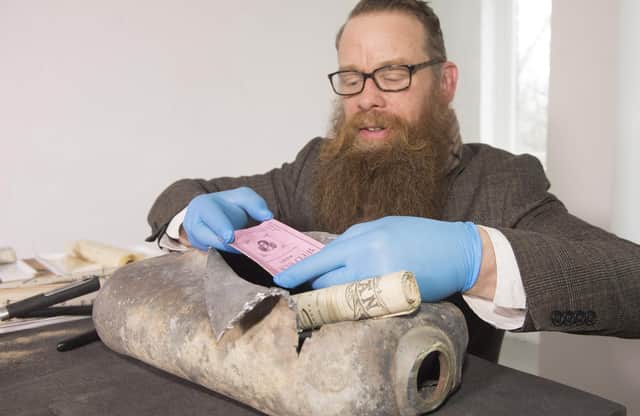 Consultant Conservator Nic Boyes opens the 1898 time capsule discovered during the move of the Burns statue on Constitution Street, Leith, Edinburgh, for the tram works