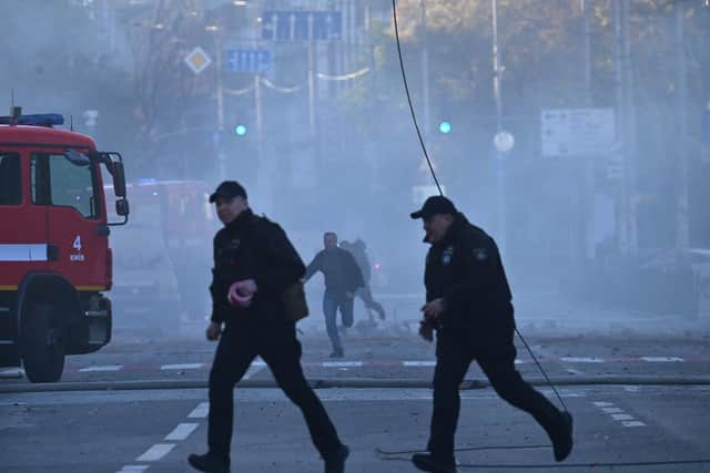Local residents and police officers run after a drone attack in Kyiv on October 17, 2022, amid the Russian invasion of Ukraine. - Ukraine officials said on October 17, 2022 that the capital Kyiv had been struck four times in an early morning Russian attack with Iranian drones that damaged a residential building and targeted the central train station. (Photo by Sergei SUPINSKY / AFP) (Photo by SERGEI SUPINSKY/AFP via Getty Images)