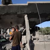 A Palestinian man holding a child looks on as children sit inside a house targeted in an Israeli strike at the Nuseirat camp for refugees in the central Gaza Strip. Picture: Eyad Baba/AFP via Getty Images