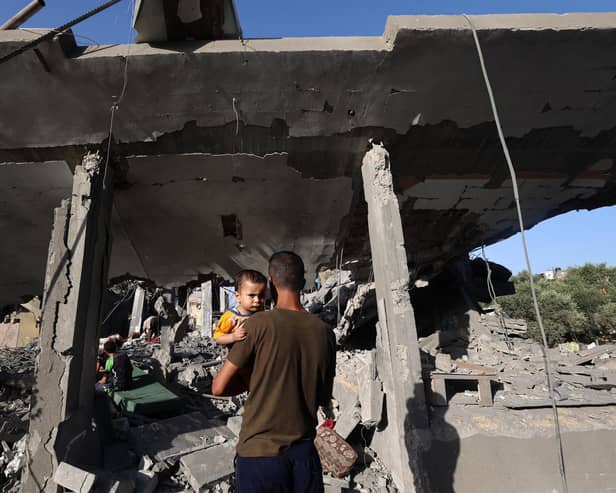 A Palestinian man holding a child looks on as children sit inside a house targeted in an Israeli strike at the Nuseirat camp for refugees in the central Gaza Strip. Picture: Eyad Baba/AFP via Getty Images