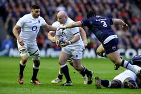 Dan Cole of England runs with the ball whilst under pressure from Zander Fagerson of Scotland.