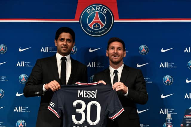 PSG's Qatari President Nasser Al-Khelaifi poses alongside Lionel Messi as he holds-up his number 30 shirt during a press conference.