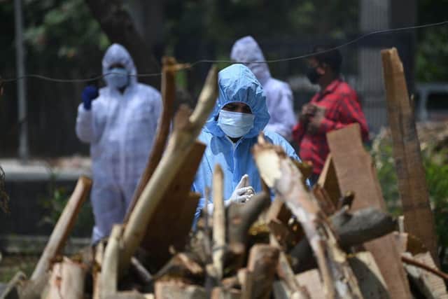 A relative wearing Personal Protective Equipment (PPR kit) performs the last rites before the cremation of a person who died due to the Covid-19 coronavirus at a cremation ground in New Delhi on May 11, 2021. (Photo by SAJJAD HUSSAIN/AFP via Getty Images)