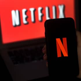 A computer screen and mobile phone display the Netflix logo. Photo by OLIVIER DOULIERY/AFP via Getty Images.