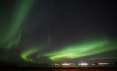 People watch the Northern Lights on a farm in Arabaer near Selfoss in Iceland.