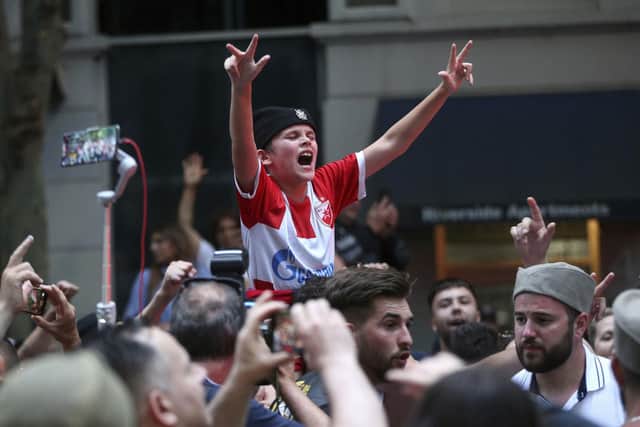 Fans of Serbian tennis star Novak Djokovic celebrate outside the Rialto building believed to be where he was located ahead of the Australian Open in Melbourne, Australia, Monday, Jan. 10, 2022. (AP Photo/Hamish Blair)