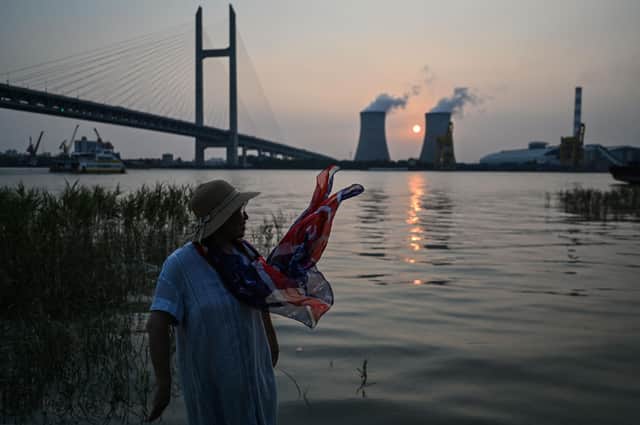 A woman looks across the Huangpu River towards the Wujing coal-fired power station in Shanghai (Picture: Hector Retamal/AFP via Getty Images)
