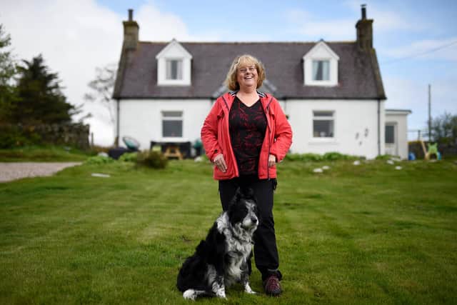 Wilma Robertson and her dog Bruiser stand in front of her croft.