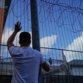 A protester communicates with those inside at the perimeter fence of Brook House immigration removal centre beside Gatwick Airport as demonstrators gather to protest against the UK government's intention to deport asylum-seekers to Rwanda.