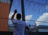 A protester communicates with those inside at the perimeter fence of Brook House immigration removal centre beside Gatwick Airport as demonstrators gather to protest against the UK government's intention to deport asylum-seekers to Rwanda.
