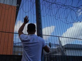 A protester communicates with those inside at the perimeter fence of Brook House immigration removal centre beside Gatwick Airport as demonstrators gather to protest against the UK government's intention to deport asylum-seekers to Rwanda.