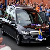 A young fan places a rose on the hearse as the funeral procession makes it's way past the Ibrox Stadium following the funeral of Rangers kitman Jimmy Bell
Pic: Andrew Milligan