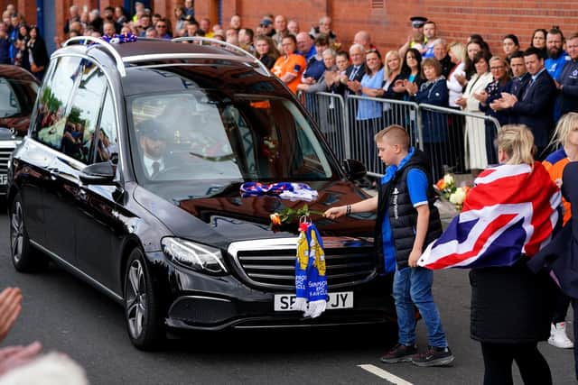 A young fan places a rose on the hearse as the funeral procession makes it's way past the Ibrox Stadium following the funeral of Rangers kitman Jimmy Bell
Pic: Andrew Milligan