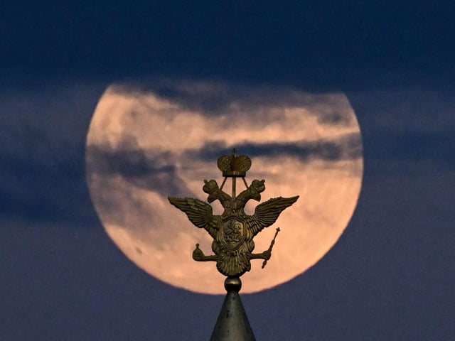 The full moon is pictured behind the two-headed eagle, the national symbol of Russia atop a building on Red Square in Moscow (Photo by KIRILL KUDRYAVTSEV/AFP via Getty Images)