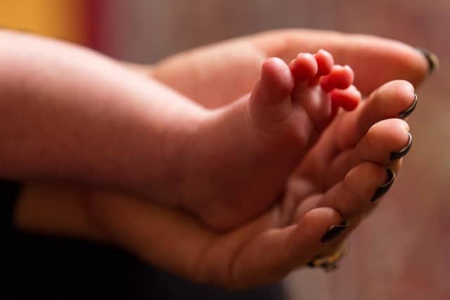 A mother holds the feet of a new baby. More babies have been admitted to hospital with the Omicron variant. Picture: PA