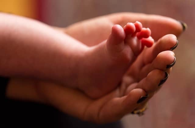 A mother holds the feet of a new baby. More babies have been admitted to hospital with the Omicron variant. Picture: PA