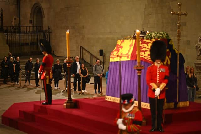 Members of the public file past, as soldiers of The Grenadier Guards and Yeomen of the Guard, stand guard around the coffin of Queen Elizabeth II, inside Westminster Hall, , London, as members of the public pay their respects as the vigil begins, where it will lie in state ahead of her funeral on Monday. Picture date: Wednesday September 14, 2022.